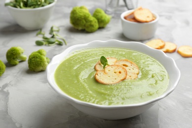 Bowl of broccoli cream soup with croutons served on grey table