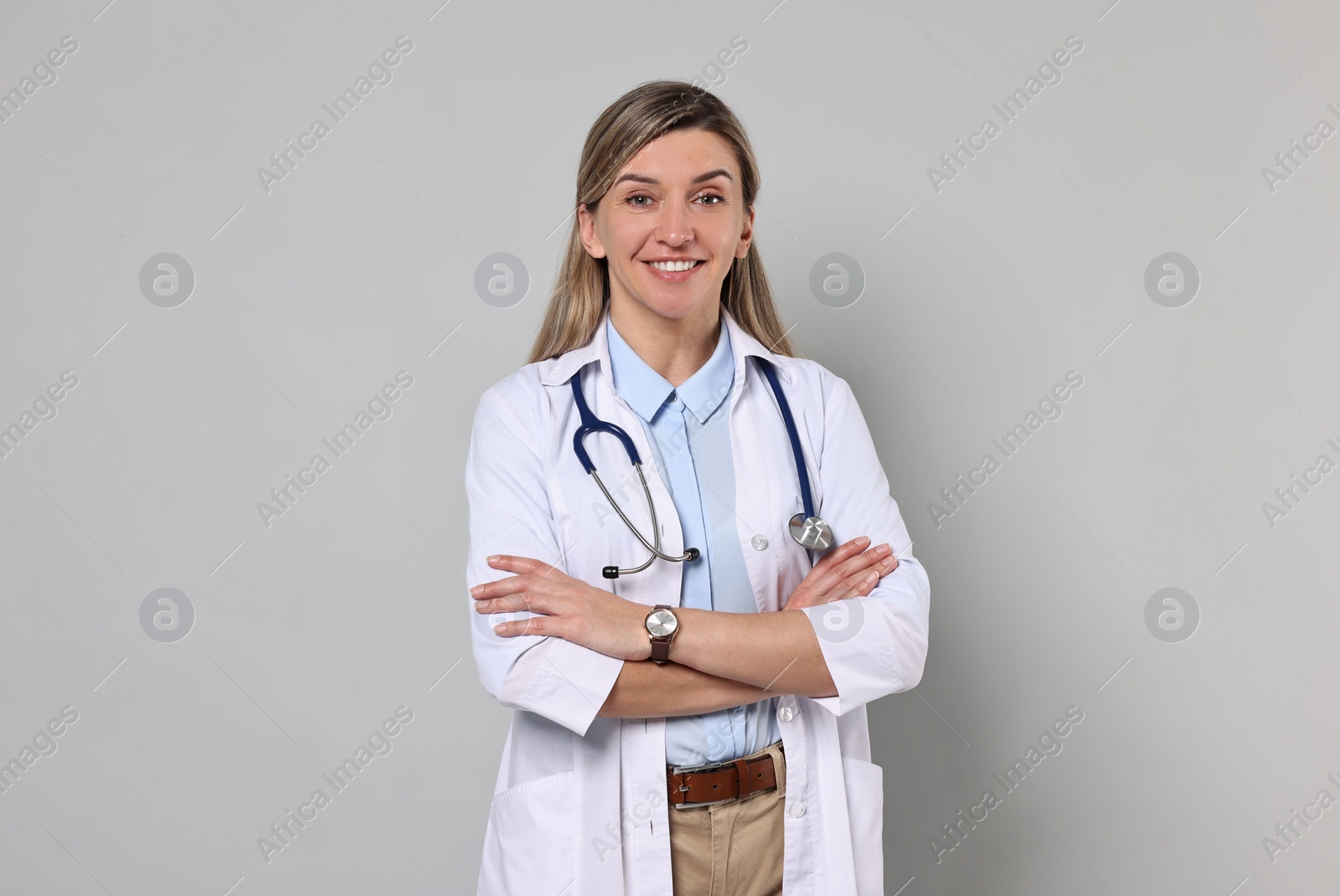 Photo of Portrait of happy doctor with stethoscope on light grey background