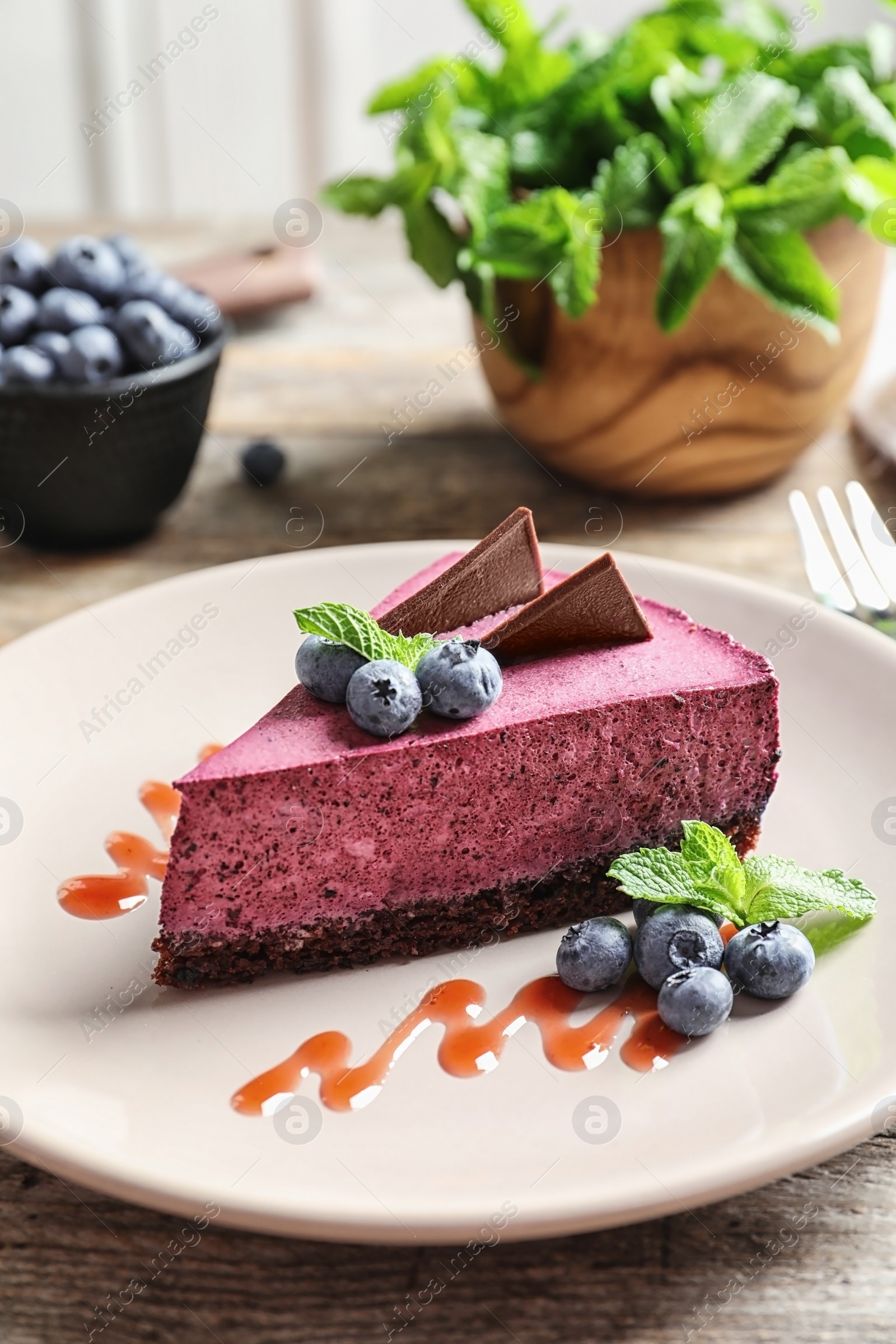 Photo of Plate with piece of tasty blueberry cake on wooden table