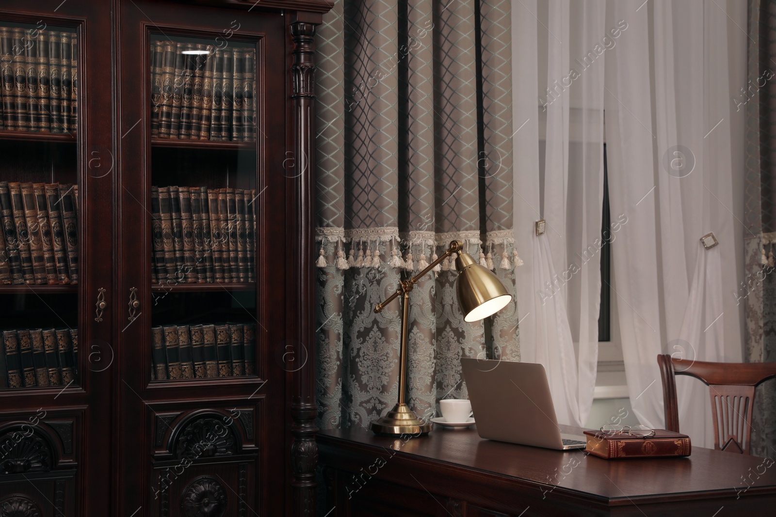 Photo of Library reading room interior with wooden bookcase and table near window