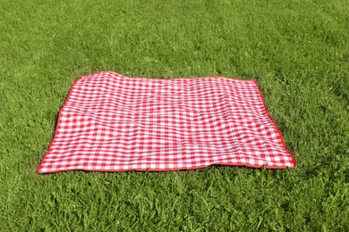 Checkered picnic tablecloth on fresh green grass outdoors