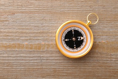 Photo of One compass on wooden table, top view. Space for text