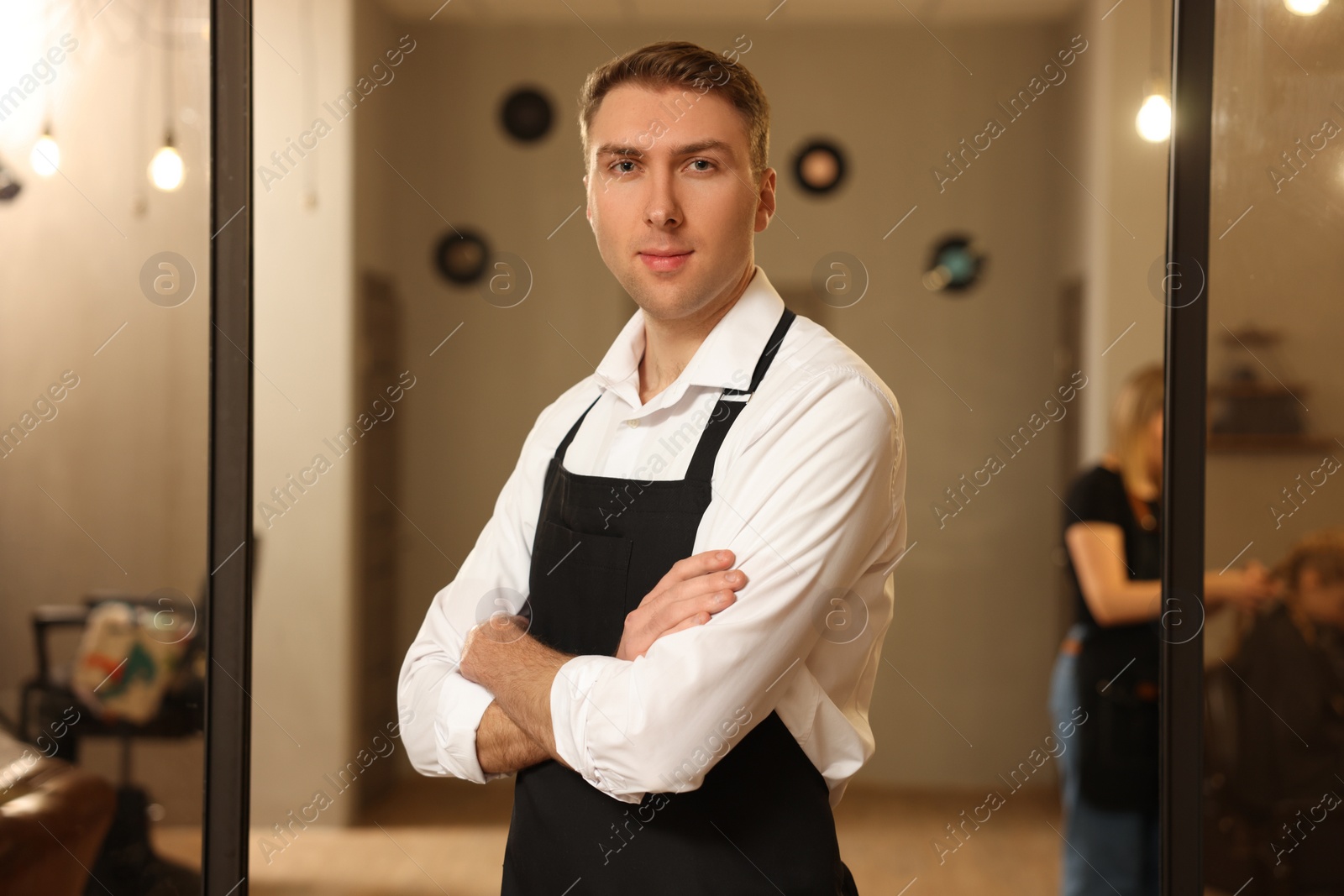 Photo of Portrait of professional hairdresser wearing apron in beauty salon