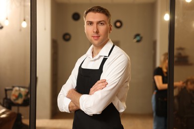 Photo of Portrait of professional hairdresser wearing apron in beauty salon