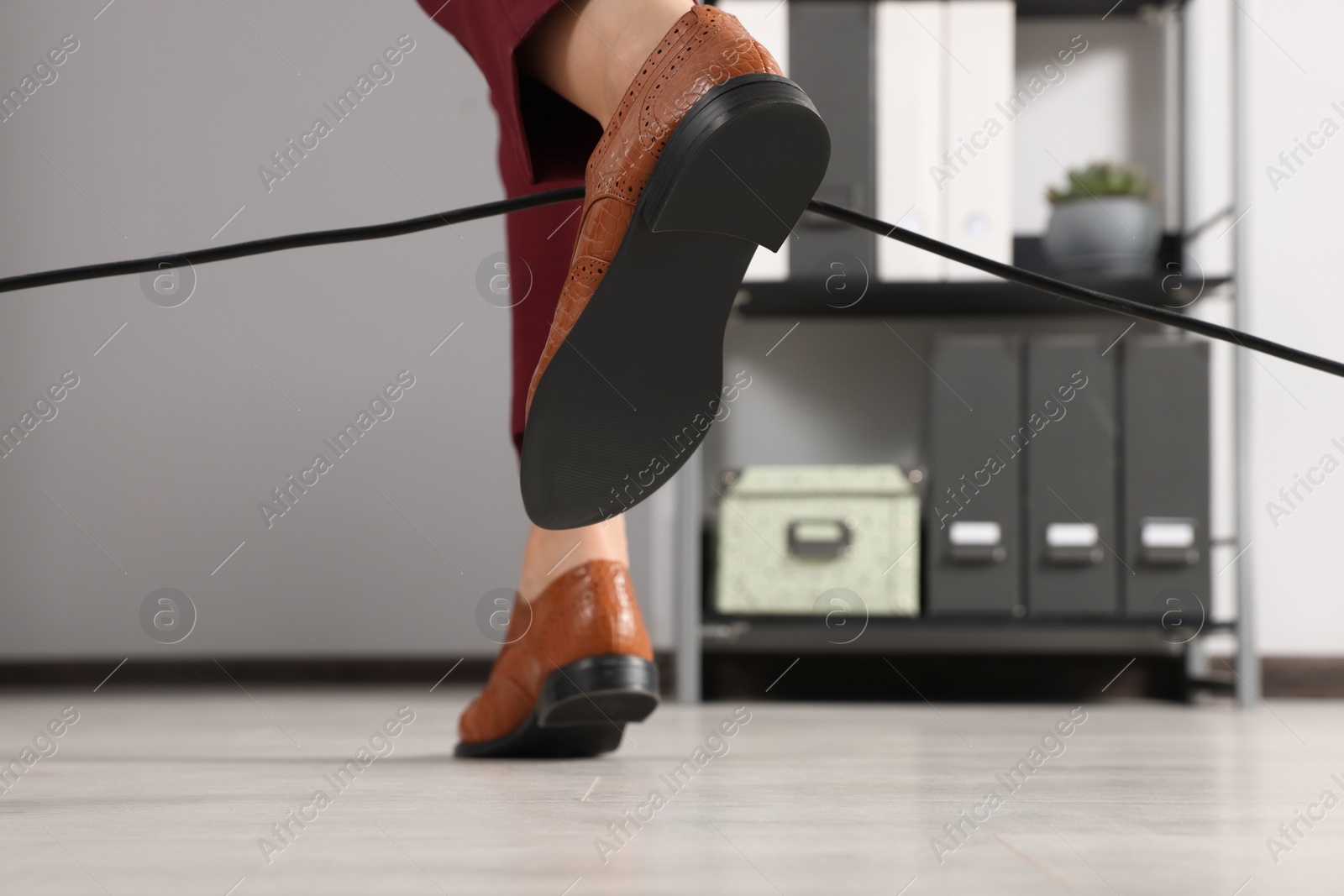 Photo of Woman tripping over cable in office, closeup