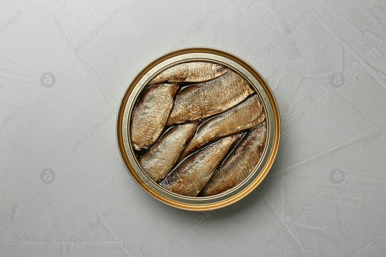 Photo of Open tin can of sprats on light grey table, top view