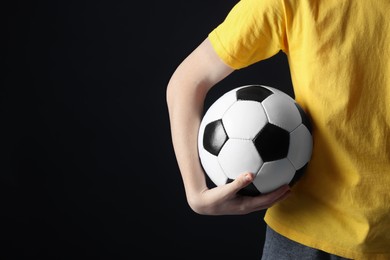 Photo of Teenage boy with soccer ball on black background, closeup. Space for text