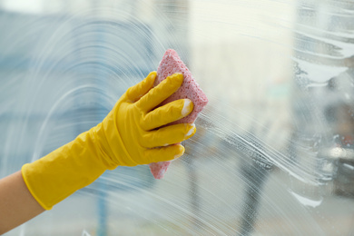 Woman cleaning window with sponge at home, closeup