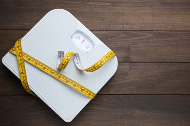 Bathroom scale, measuring tape and space for text on wooden floor, top view. Weight loss concept