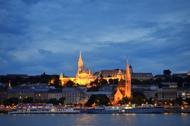 Photo of BUDAPEST, HUNGARY - JUNE 17, 2018: Picturesque view of Danube river with Matthias Church and Fishermen's Bastion in evening