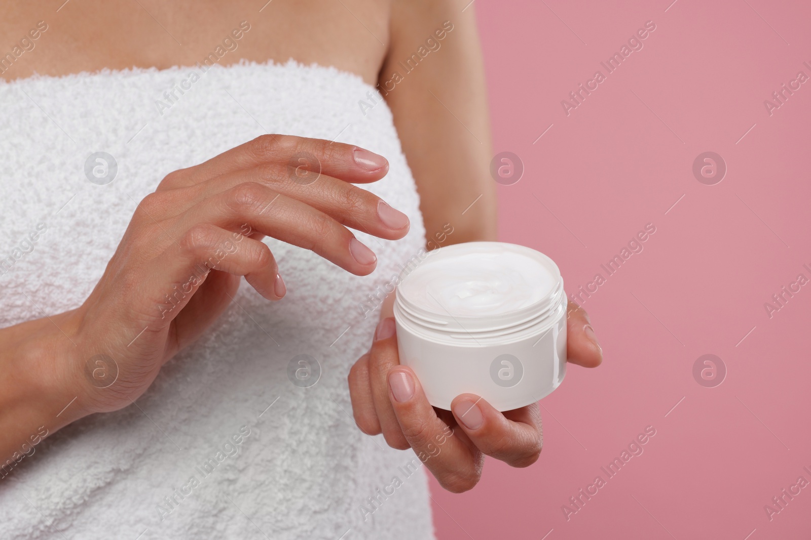 Photo of Woman holding body cream on pink background, closeup. Space for text