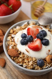 Photo of Tasty granola, yogurt and fresh berries in bowl on wooden board, closeup. Healthy breakfast