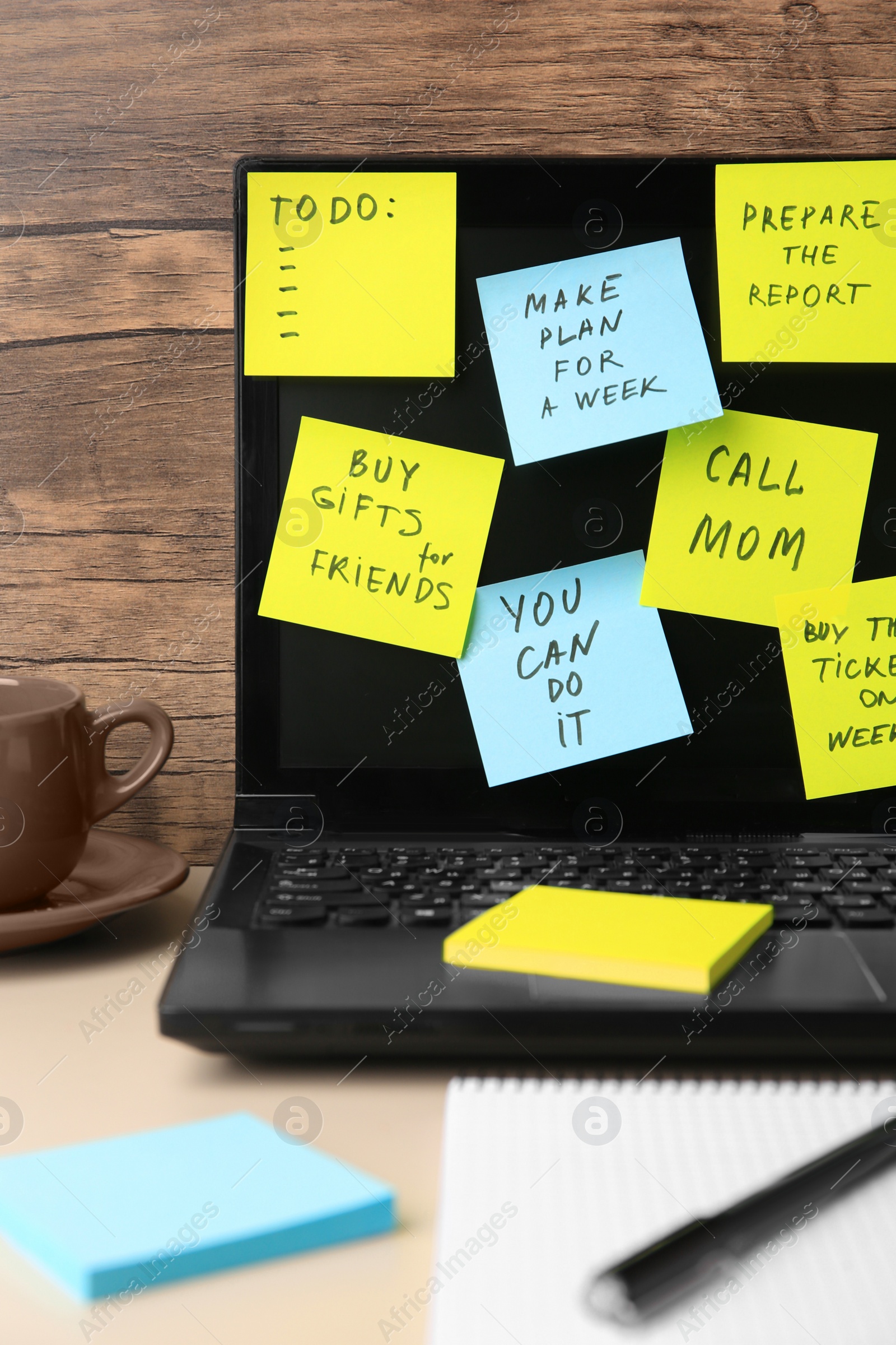 Photo of Laptop with reminder notes on beige desk indoors