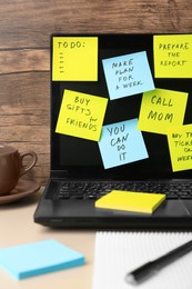 Photo of Laptop with reminder notes on beige desk indoors