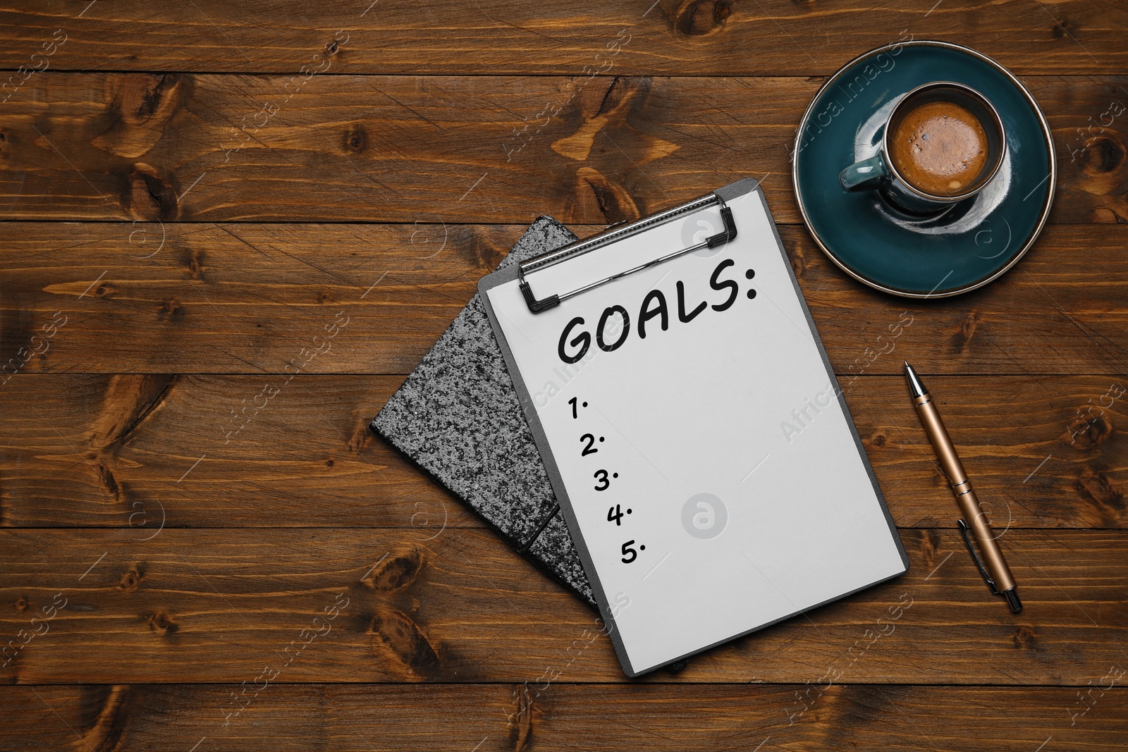 Image of Notebook with inscription Goals, cup of coffee and pen on wooden table, flat lay. New Year aims 