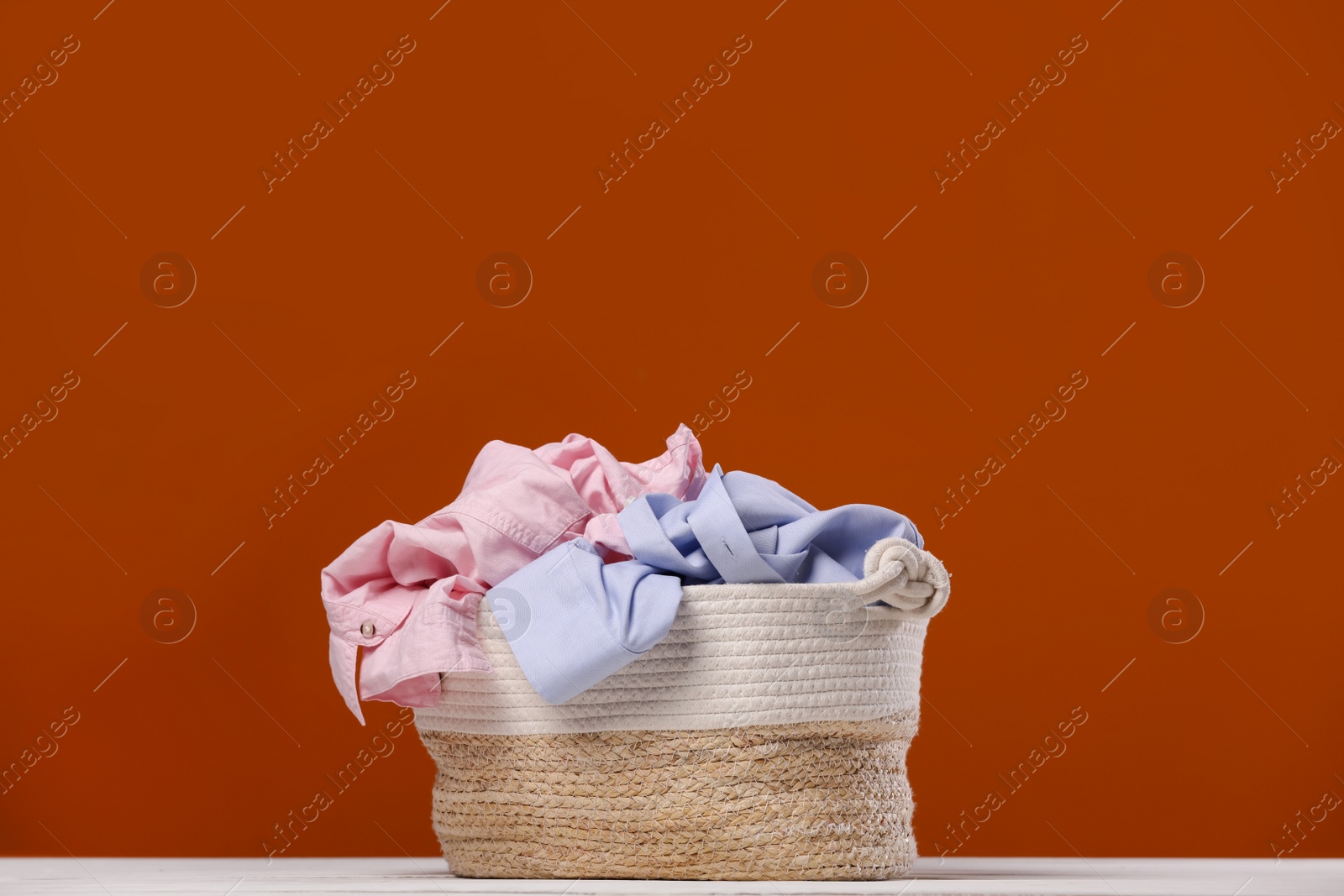 Photo of Laundry basket with clothes near brown wall