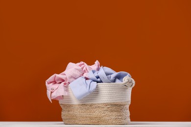 Laundry basket with clothes near brown wall