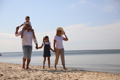 Photo of Cute little children with grandparents spending time together on sea beach