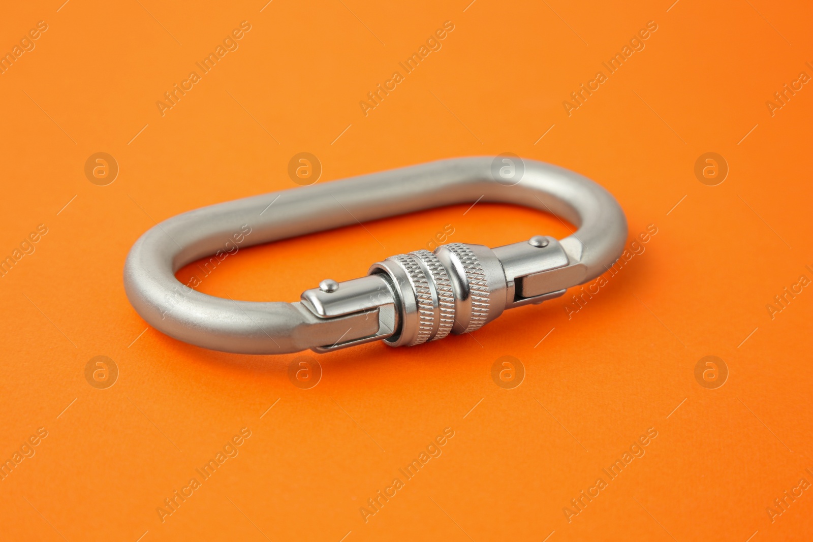 Photo of One metal carabiner on orange background, closeup