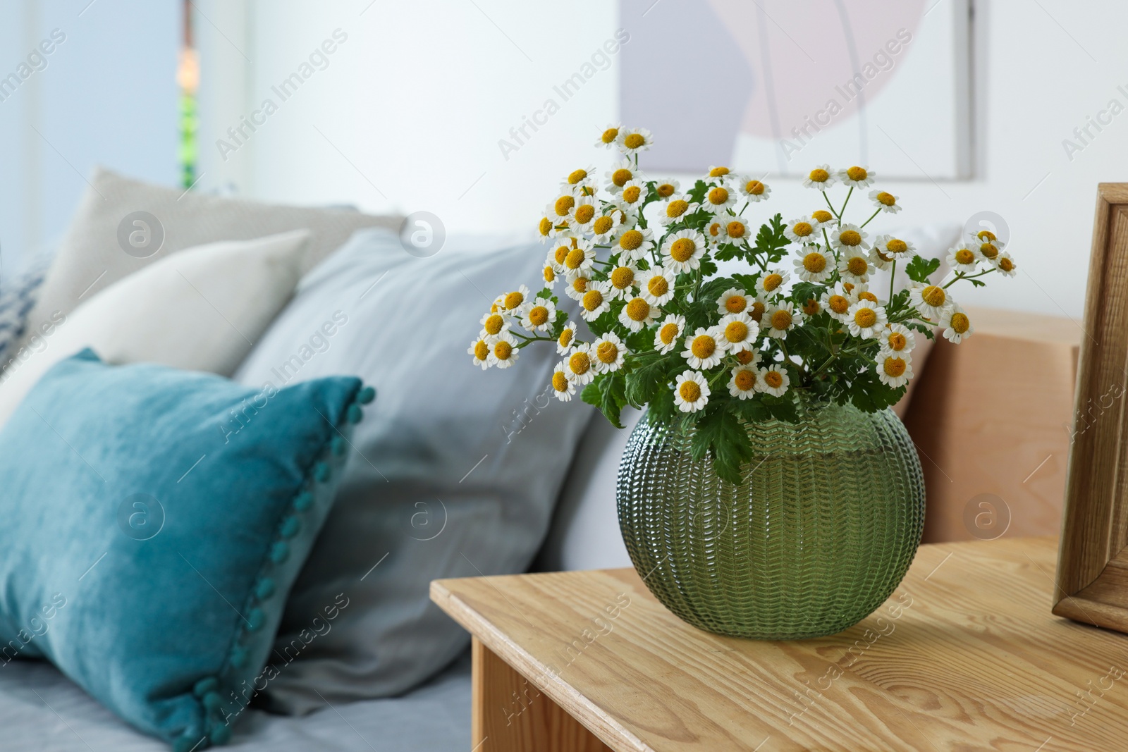 Photo of Beautiful bouquet of chamomile flowers on wooden nightstand in bedroom, space for text. Interior element