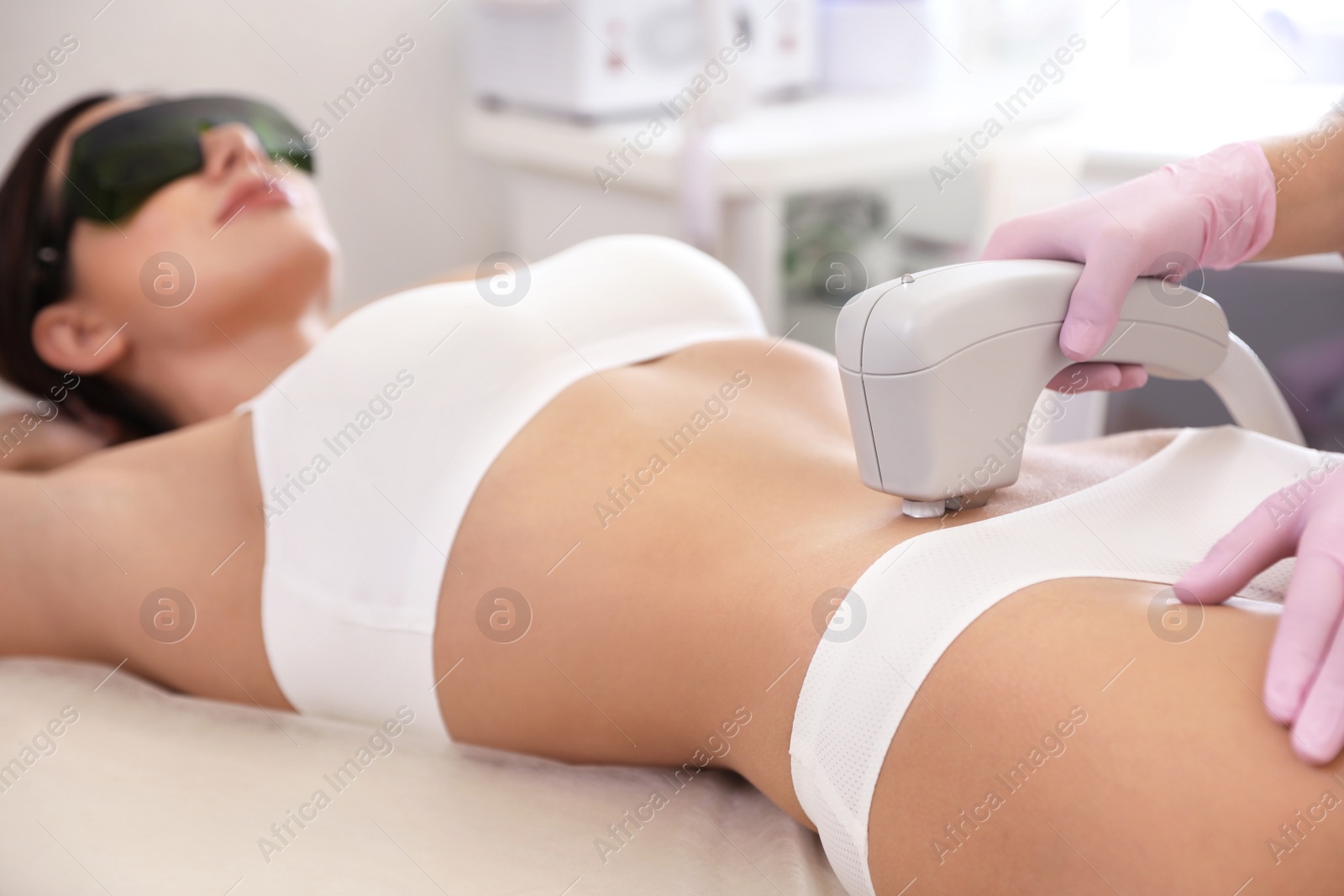 Photo of Young woman undergoing laser epilation procedure in beauty salon