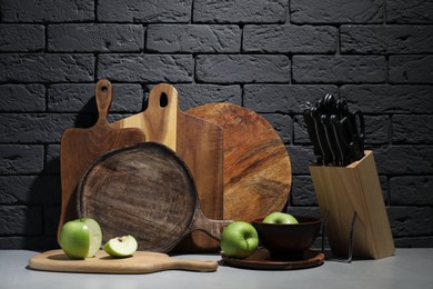 Photo of Wooden cutting boards, apples and knives on gray table