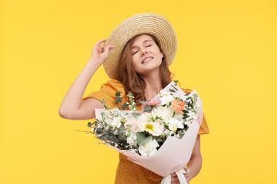 Photo of Happy woman in straw hat with bouquet of beautiful flowers on yellow background