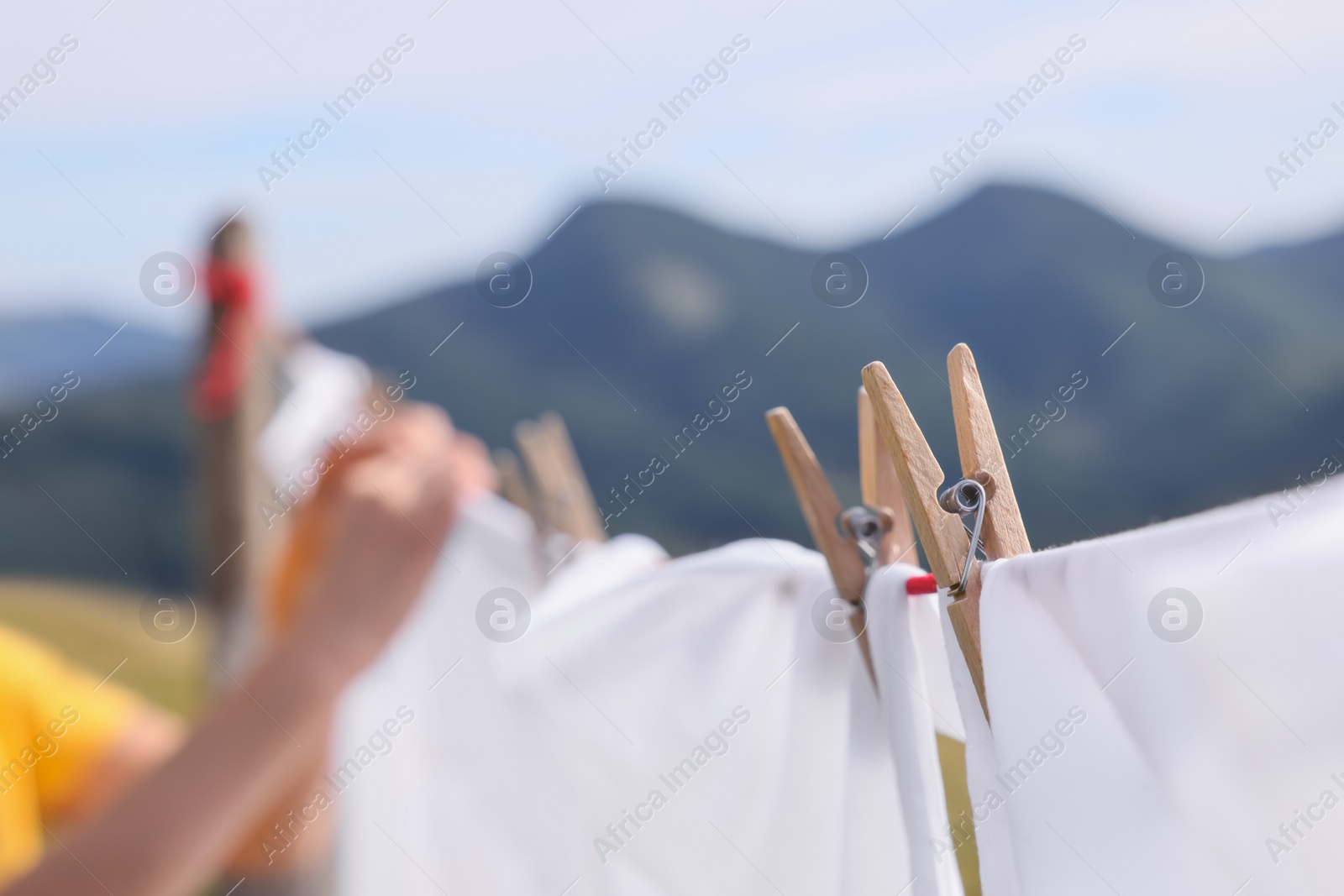 Photo of Washing line with clean laundry and clothespins in mountains, closeup