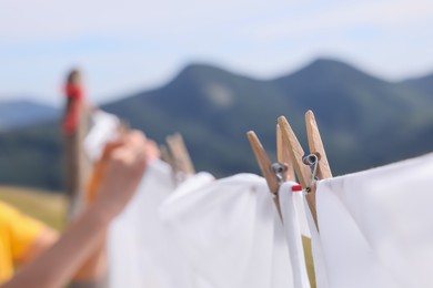 Washing line with clean laundry and clothespins in mountains, closeup