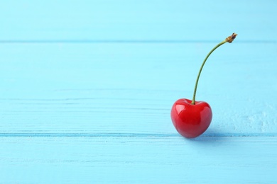 Photo of Ripe red cherry on blue wooden background