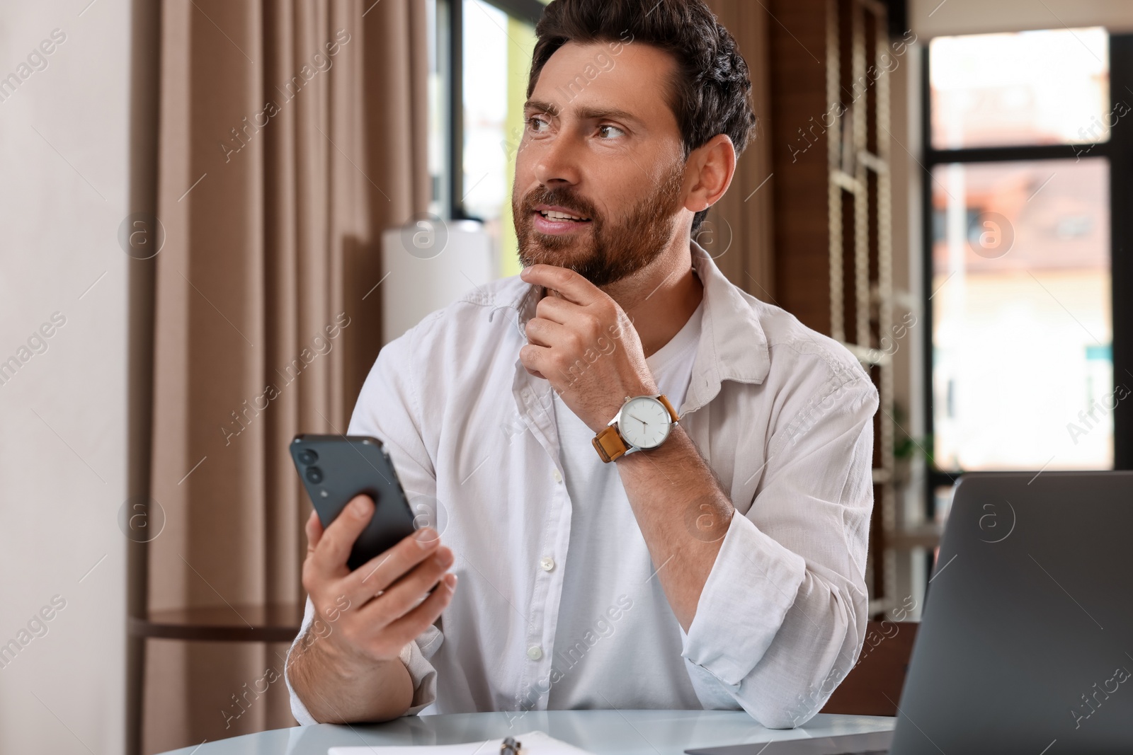 Photo of Handsome man talking on phone at table in cafe