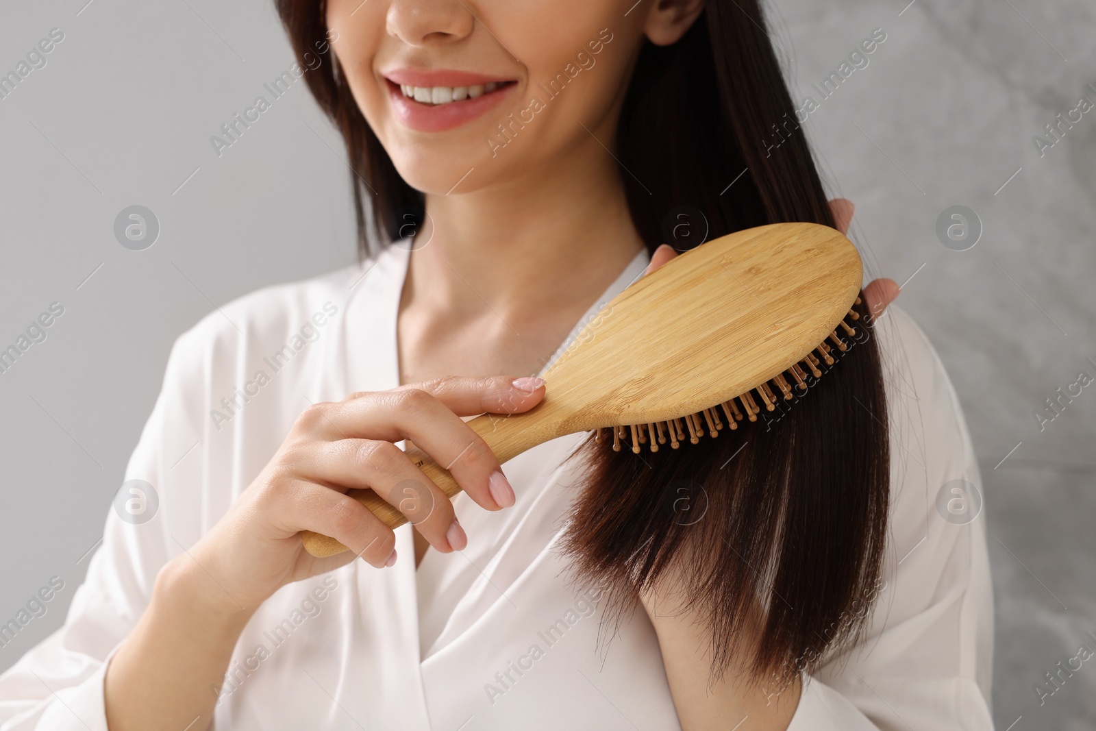 Photo of Woman brushing her hair indoors, closeup view