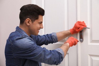 Photo of Handyman with screwdriver repairing door lock indoors