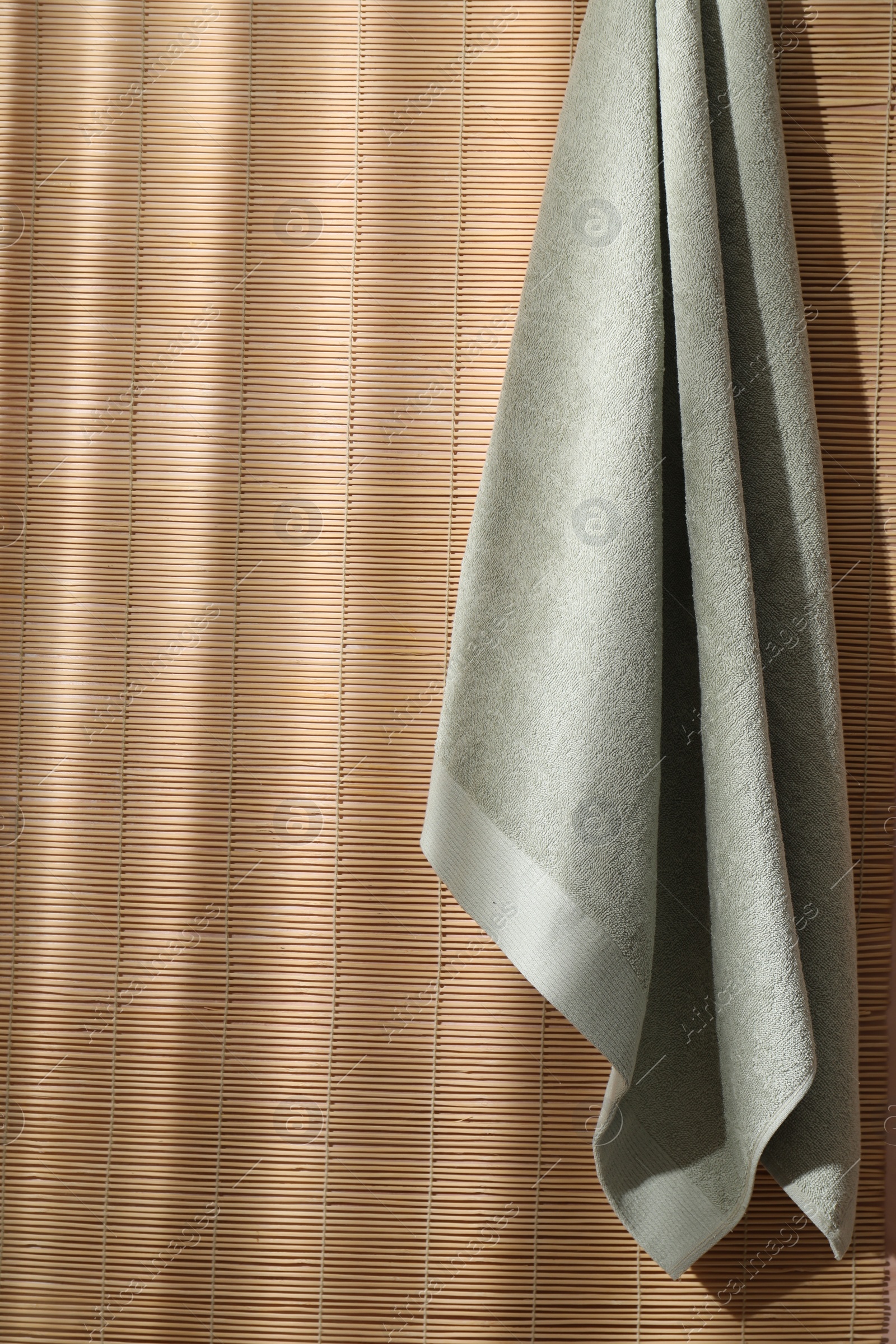 Photo of Soft towel hanging on bamboo wall indoors, space for text