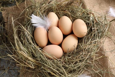 Photo of Fresh raw chicken eggs in nest on grey wooden table, above view