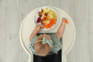 Photo of Cute little girl eating healthy food, top view
