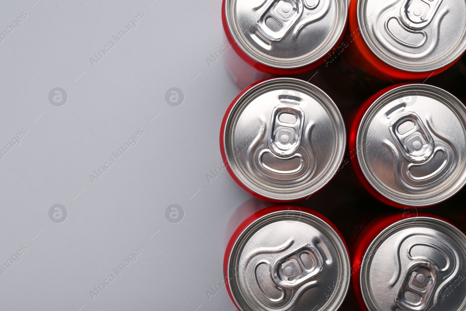 Photo of Energy drink in cans on grey background, top view. Space for text