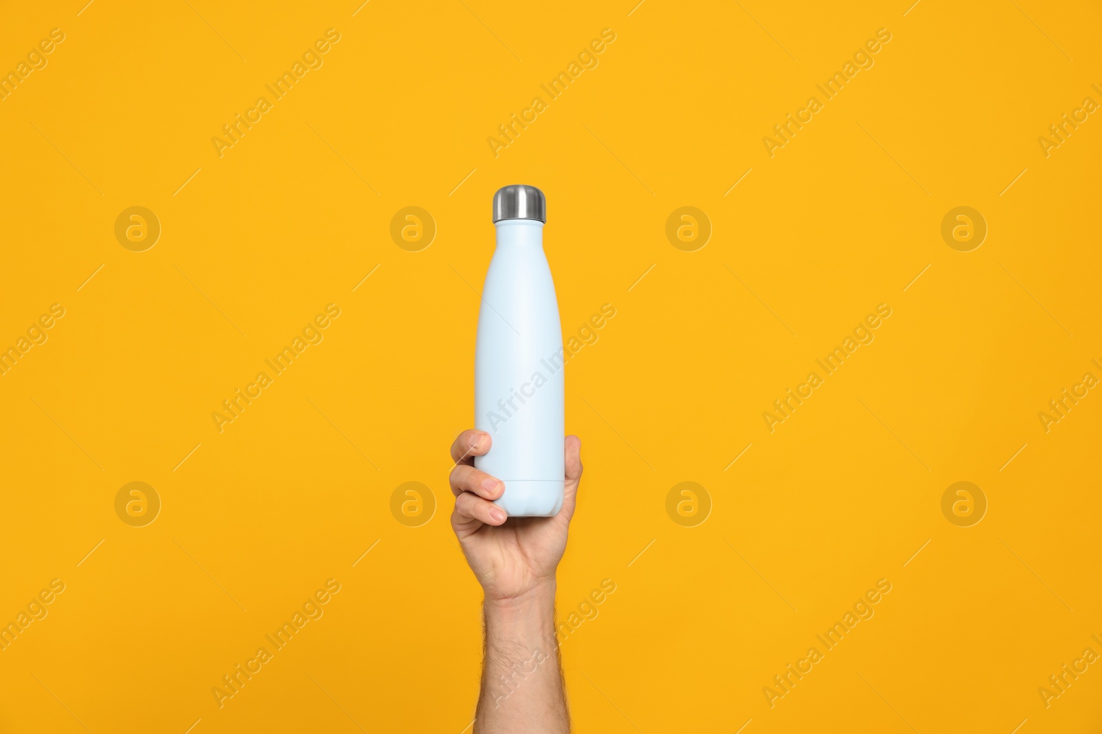 Photo of Man holding thermo bottle on orange background, closeup