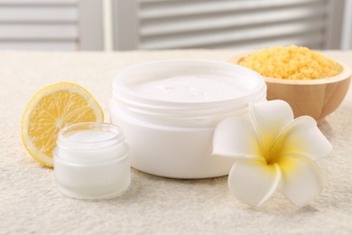 Composition with body care cream in open jars on light textured table, closeup