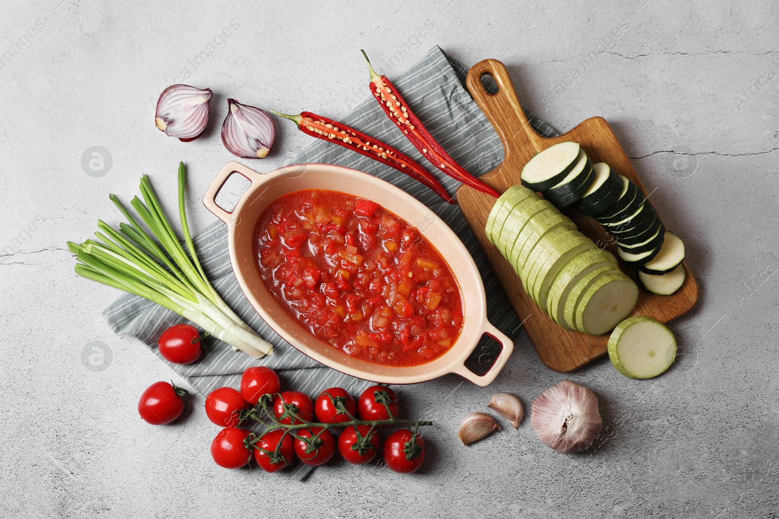 Photo of Dressing for ratatouille and different fresh vegetables on light grey table, flat lay