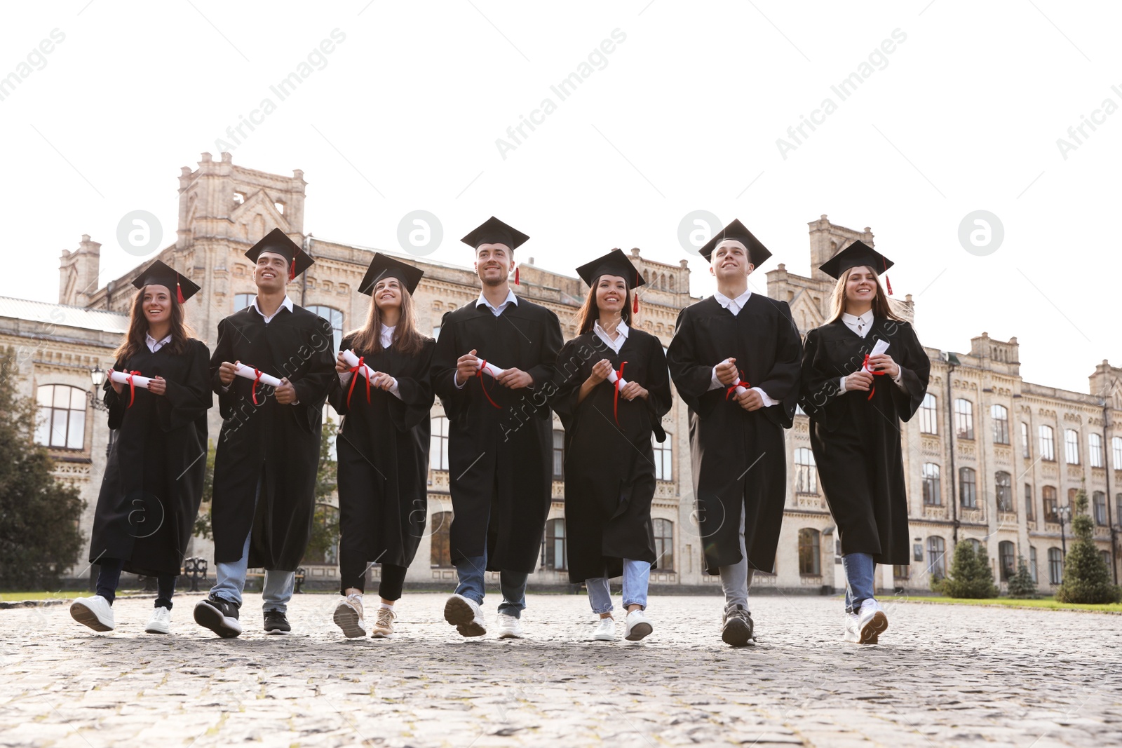 Photo of Happy students with diplomas outdoors. Graduation ceremony