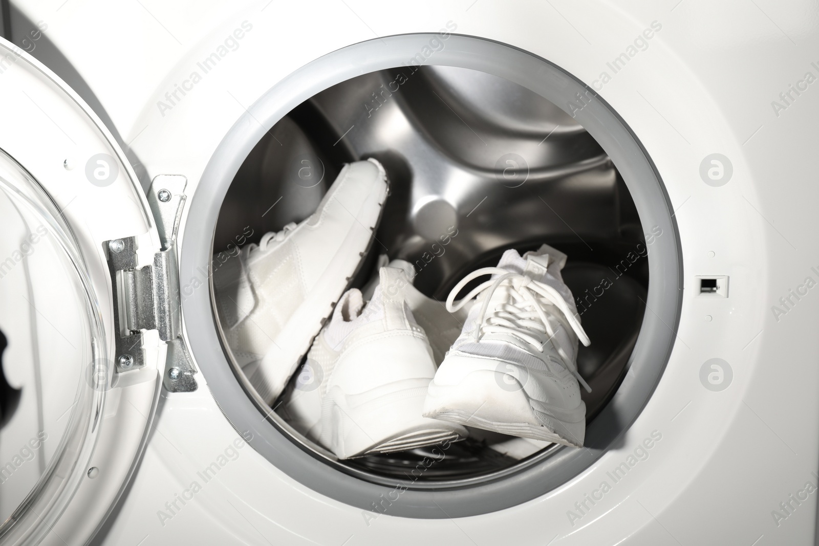 Photo of Stylish clean sneakers inside modern washing machine