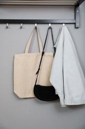 Photo of Bags and clothes on coat rack in hallway. Interior element