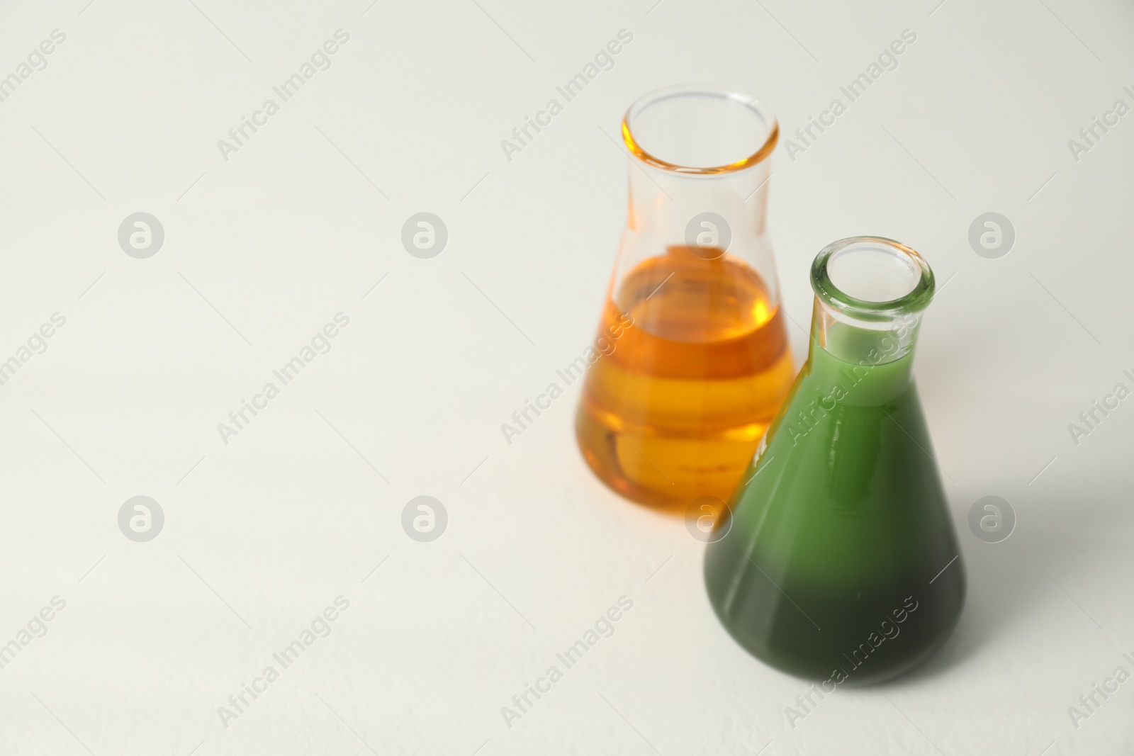 Photo of Glass flasks with different types of oil on white table, space for text
