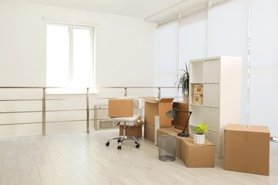 Photo of Cardboard boxes with packed stuff in new office, space for text. Moving day