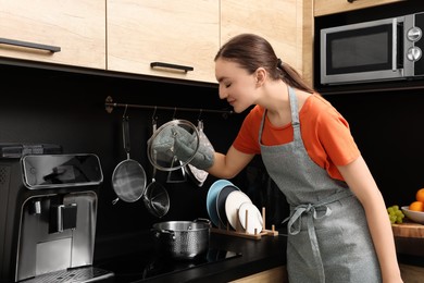 Photo of Young woman cooking dish in pot at kitchen