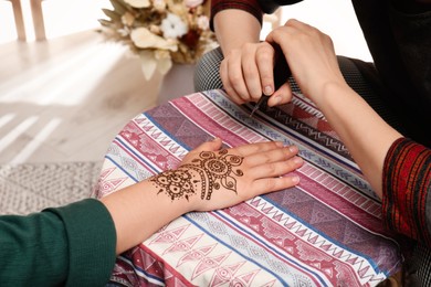 Photo of Master making henna tattoo on hand, closeup. Traditional mehndi