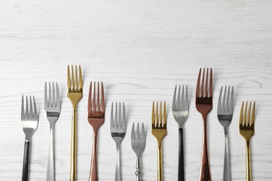 Photo of Flat lay composition with different forks on white wooden background, space for text