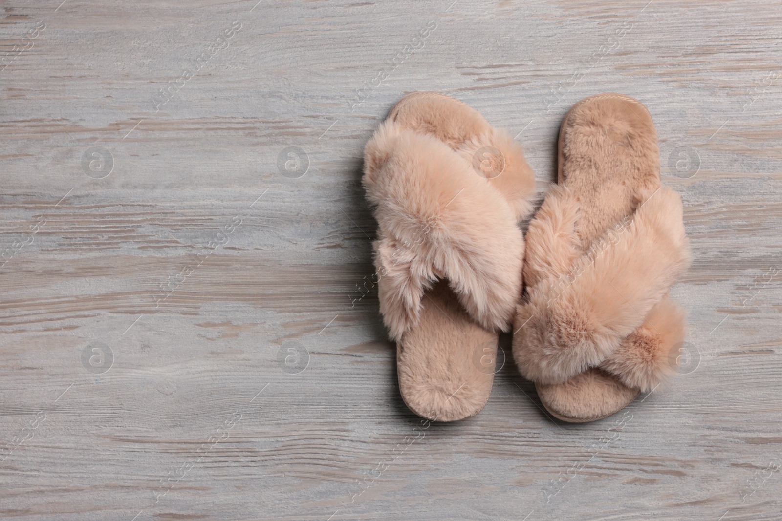 Photo of Pair of soft slippers on white wooden floor, top view. Space for text