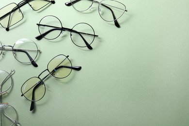 Photo of Many different stylish glasses on light green background, flat lay. Space for text